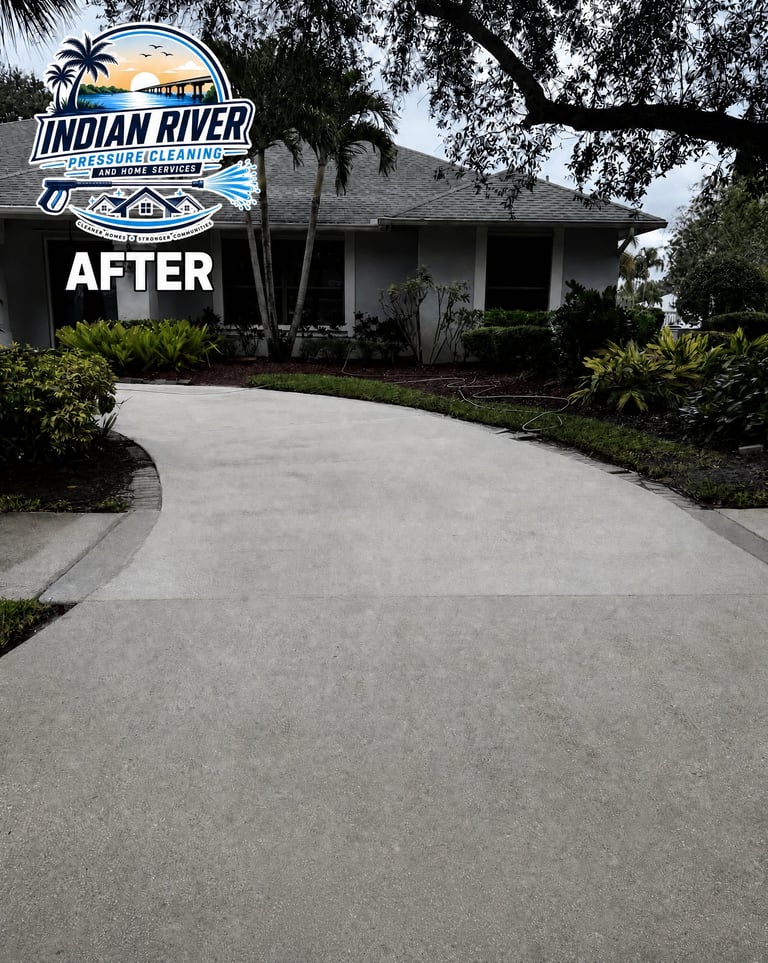 After renovation of concrete driveway at home with palm trees and manicured landscaping. Indian River Pressure Cleaning logo displayed
